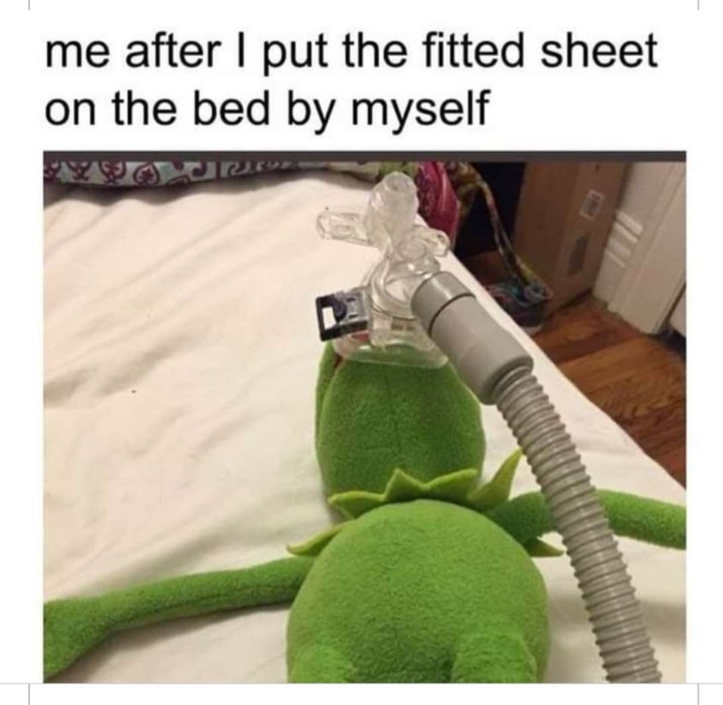 A meme of Kermit the Frog lying on a bed with a medical oxygen mask over his face. Text says "me after I put the fitted sheet on the bed by myself."