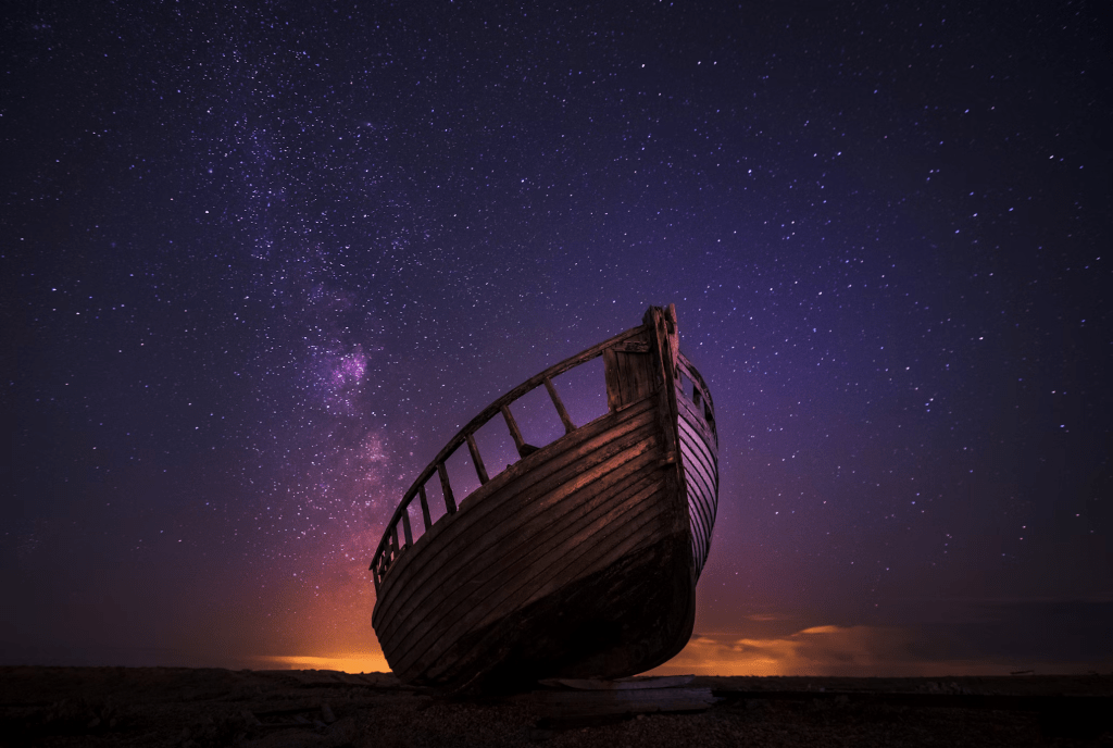 Photo by Zoltan Tasi on Unsplash

Photograph of the bow of a wooden boat under a starry night sky